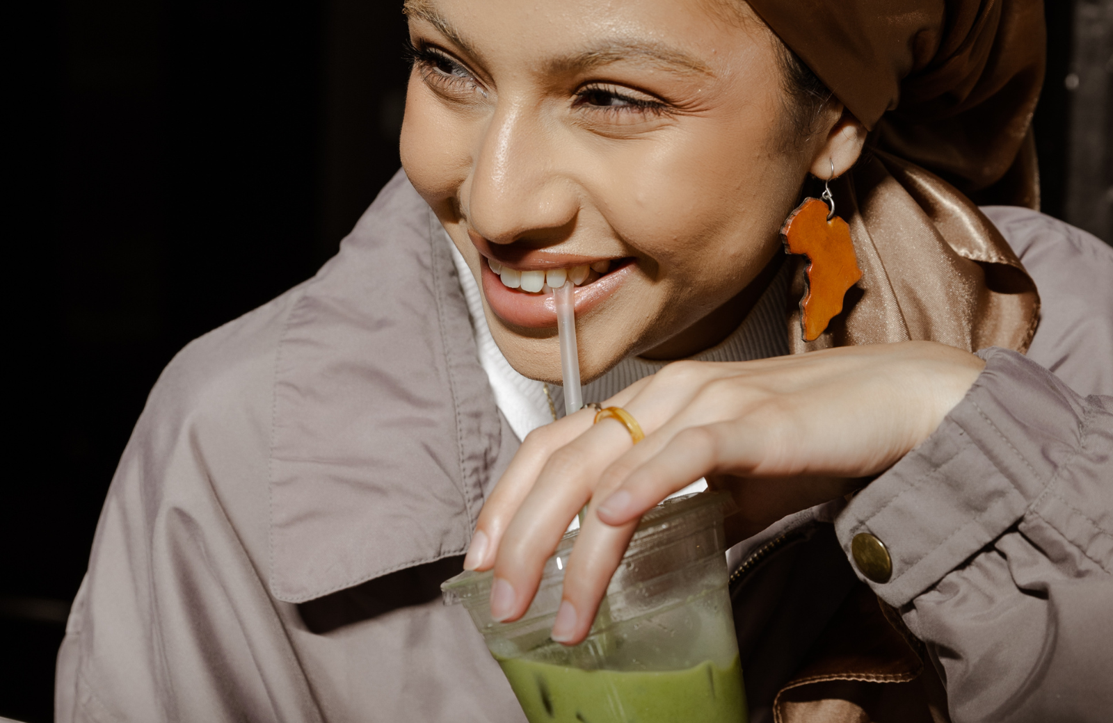 jonge vrouw drinkt een matcha smoothie door een rietje